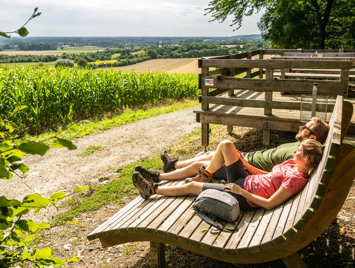 Borgholzhausen-Aussichtsplattform Berghauser Weg-Teutoburger-Wald-Tourismus-D-Ketz-071.jpg Holzplattform mit Entspannungsliegen und weitem Blick über grüne Felder und sanfte Hügel im Sommer.
