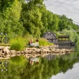 Minden-Schiffmühle-Teutoburger-Wald-Tourismus-Patrick-Gawandtka-021.jpg Personen sitzen entspannt am Flussufer der Weser bei Minden; Fahrräder, eine alte Hütte, und Brücke.