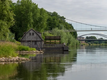 Minden-Schiffmühle-Teutoburger-Wald-Tourismus-Patrick-Gawandtka-029-CC-BY-SA.jpg Historische Wassermühle an der Weser bei Minden, umgeben von grünen Bäumen unter grauem Himmel.