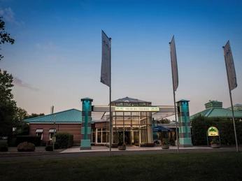 Driburg Therme - Außenansicht Eingang der Driburg Therme mit modernem Glas- und Backsteinbau, umgeben von grüner Vegetation.
