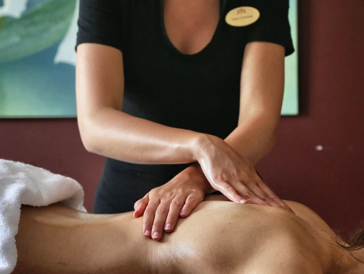Spa im Gräflichen Park Eine Masseurin in schwarzer Kleidung führt eine Rückenmassage durch; im Hintergrund ist ein abstraktes Bild.