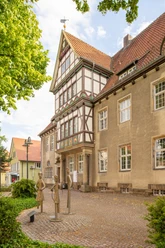 Fachwerkgebäude mit verziertem Giebel, dekorativer Fassade und Skulpturen auf einem Pflasterplatz.