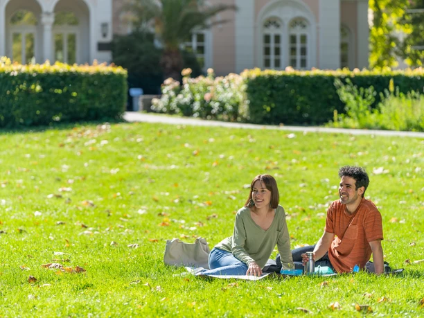 Ein Mann und eine Frau sitzen auf dem Rasen in Arminiuspark in Bad Lippspringe