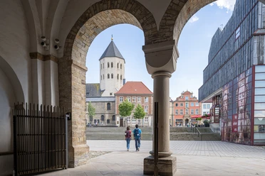 Paderborn-Dom-Teutoburger-Wald-Tourismus-Patrick-Gawandtka-071.jpg Blick durch einen Torbogen auf den Dom in Osnabrück, zwei Personen spazieren in Richtung des Platzes.