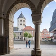 Paderborn-Dom-Teutoburger-Wald-Tourismus-Patrick-Gawandtka-071.jpg Blick durch einen Torbogen auf den Dom in Osnabrück, zwei Personen spazieren in Richtung des Platzes.