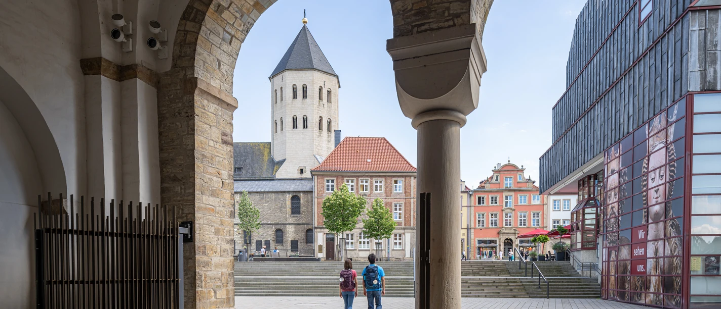 Paderborn-Dom-Teutoburger-Wald-Tourismus-Patrick-Gawandtka-071.jpg Blick durch einen Torbogen auf den Dom in Osnabrück, zwei Personen spazieren in Richtung des Platzes.