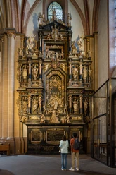 Ein kunstvoll verzierter, mehrstöckiger Altar mit zahlreichen religiösen Figuren in einer Kirche.