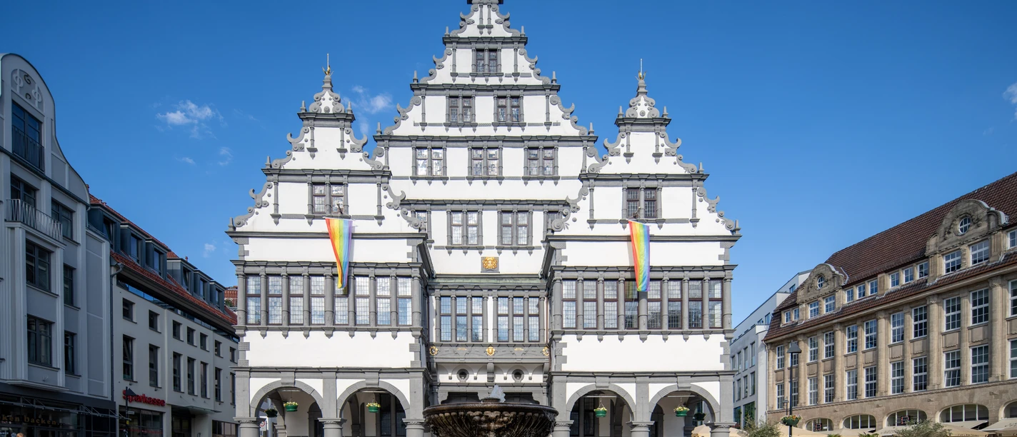 Paderborn-Rathaus-Teutoburger-Wald-Tourismus-Patrick-Gawandtka-095.jpg Ein historisches Rathaus mit markanter Fassade und Brunnen im Vordergrund, bei blauem Himmel gezeigt.