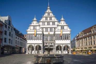 Paderborn-Rathaus-Teutoburger-Wald-Tourismus-Patrick-Gawandtka-096-CC-BY-SA.jpg Renaissance-Rathaus mit prächtiger Fassade und Schaugiebeln, im Vordergrund ein runder Brunnen.