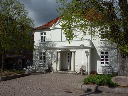 Alte Wache 2.JPG Alte Wache am Marktplatz, weißes Gebäude mit rotem Dach, links und rechts Bäume, davor Platz und Gehwege