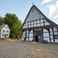 Bielefeld-Bauernhausmuseum-Teutoburger-Wald-Tourismus-T-Evers-049.jpg Fachwerkhäuser des Museums Bauernhaus Bielefeld, umgeben von Bäumen, bei sonnigem Wetter.