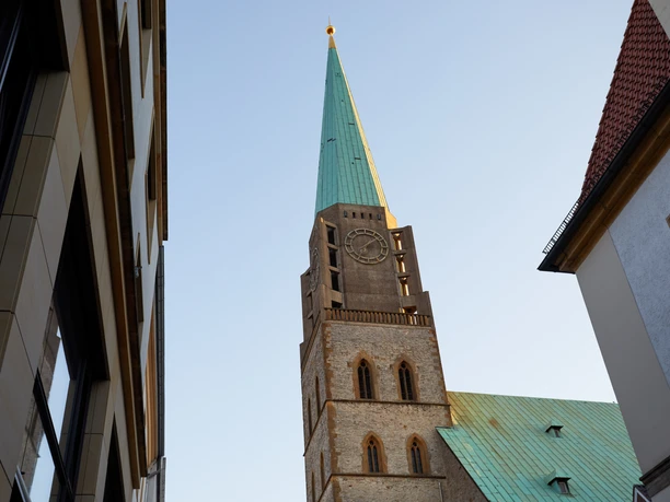 Bielefeld-Evangelische Kirche von Westfalen-Teutoburger-Wald-Tourismus-T-Evers-004.jpg Kirche mit hohem, grünem Turm zwischen Gebäuden bei blauem Himmel, in Bielefeld aufgenommen.