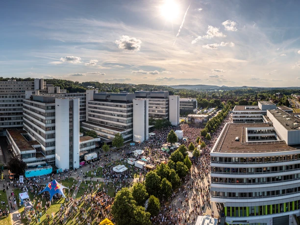 Bielefeld-CampusFestival22-Teutoburger-Wald-Tourismus-Patrick-Gawandtka-100.jpg Panorama des Universitätsgeländes Bielefeld mit Gebäuden, Menschenmengen und sonnigem Himmel.
