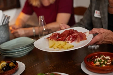 Bielefeld-Gastronomie-Teutoburger-Wald-Tourismus-T-Evers-077.jpg Ein Tisch mit Tapas, darunter Schinken, Käse und Oliven, wird in einem Restaurant serviert.