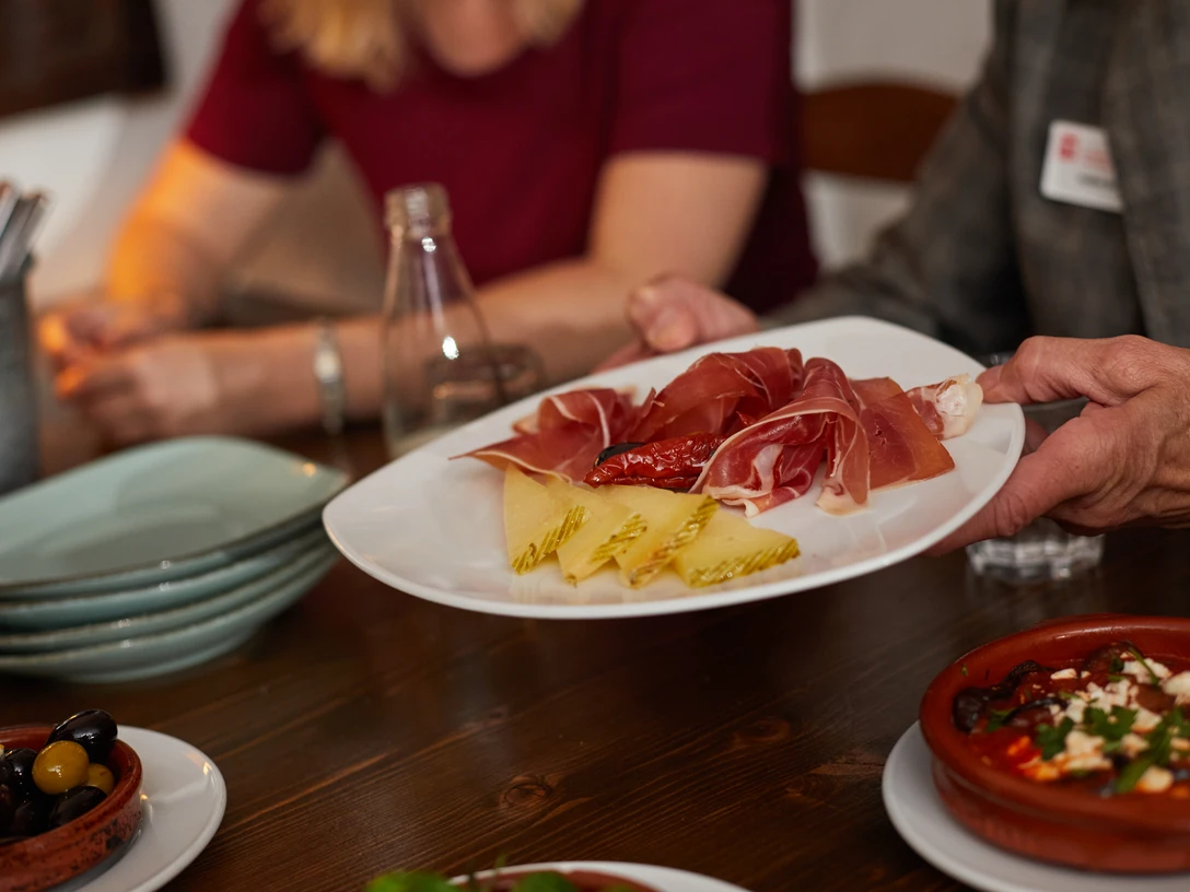 Bielefeld-Gastronomie-Teutoburger-Wald-Tourismus-T-Evers-077.jpg Ein Tisch mit Tapas, darunter Schinken, Käse und Oliven, wird in einem Restaurant serviert.