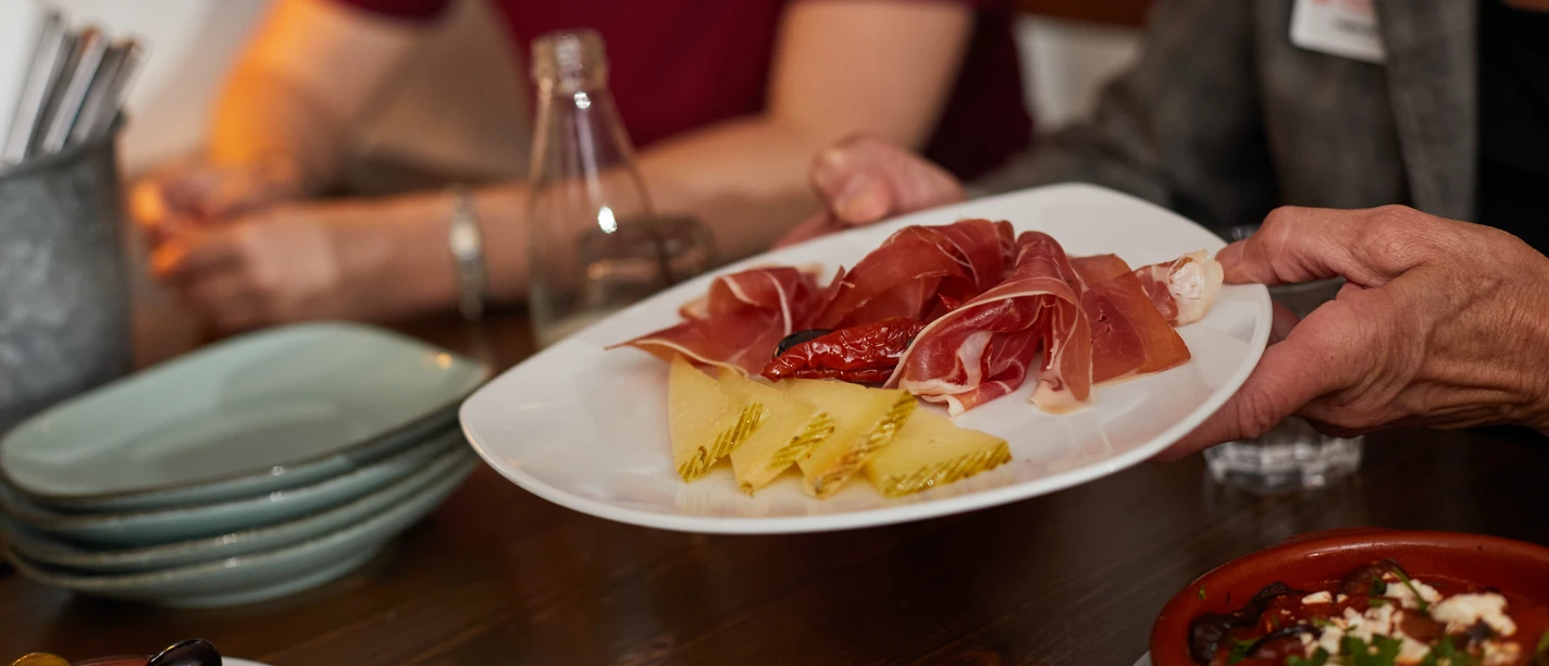 Bielefeld-Gastronomie-Teutoburger-Wald-Tourismus-T-Evers-077.jpg Ein Tisch mit Tapas, darunter Schinken, Käse und Oliven, wird in einem Restaurant serviert.