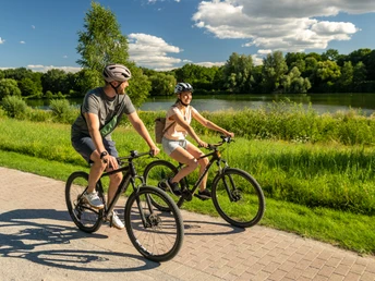 Bielefeld-Obersee-Teutoburger-Wald-Tourismus-D-Ketz-076.jpg <p>Ein Mann und eine Frau fahren bei sonnigem Wetter auf Fahrrädern entlang eines grünen Flussufers.</p>