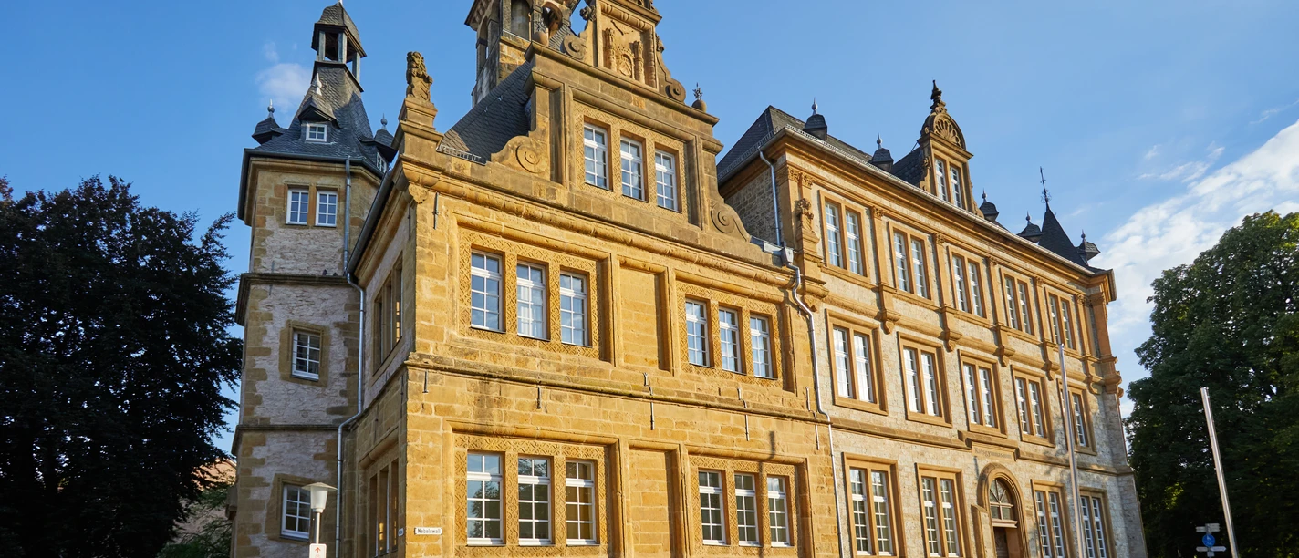 Bielefeld-Ratsgymnasium-Teutoburger-Wald-Tourismus-T-Evers-091.jpg Historisches Gebäude in Bielefeld aus Sandstein mit Türmen und Ornamenten bei sonnigem Wetter.