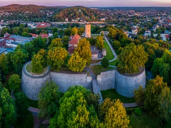 Panoramablick auf die Sparrenburg in Bielefeld, umgeben von üppigem Grün und Stadtlandschaft.