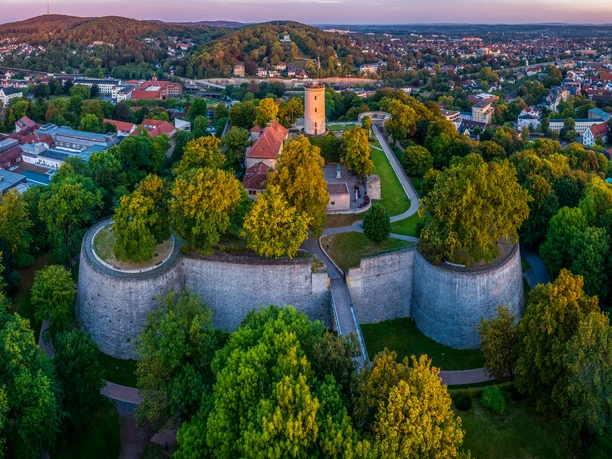 Bielefeld-Sparrenburg-Teutoburger-Wald-Tourismus-D-Ketz-009-CC-BY-SA.jpg Panoramablick auf die Sparrenburg in Bielefeld, umgeben von üppigem Grün und Stadtlandschaft.