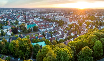 Bielefeld-Sparrenburg-Teutoburger-Wald-Tourismus-D-Ketz-012.jpg <p>Luftaufnahme einer Stadt bei Sonnenuntergang mit Kirche, Wohnhäusern und Bäumen im Vordergrund.</p>