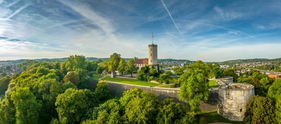 Bielefeld-Sparrenburg-Teutoburger-Wald-Tourismus-D-Ketz-046.jpg Die Sparrenburg in Bielefeld thront majestätisch auf einem bewaldeten Hügel unter blauem Himmel.