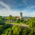 Bielefeld-Sparrenburg-Teutoburger-Wald-Tourismus-D-Ketz-046.jpg Die Sparrenburg in Bielefeld thront majestätisch auf einem bewaldeten Hügel unter blauem Himmel.