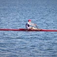 Ruderregatta (2).jpg Blick auf den See, ein Mann sitzt in einem Ruderboot auf dem Wasser.