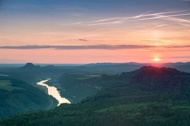 View from the Kipphorn View Sunset over a river landscape with green hills and a clear sky glowing in warm pastel shades.