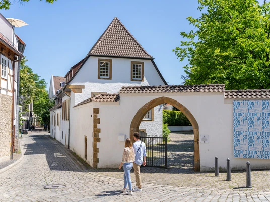 Bielefeld-Welle-Teutoburger-Wald-Tourismus-Patrick-Gawandtka-057.jpg <p>Pärchen spaziert auf gepflasterter Gasse zu historischem Torbogen in sonniger Altstadt.</p>