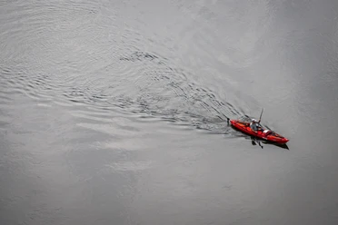 Beverungen-Weser Skywalk-Teutoburger-Wald-Tourismus-D-Ketz-021.jpg Ein rotes Kajak mit zwei Personen, die auf einem ruhigen Fluss paddeln, von oben gesehen.