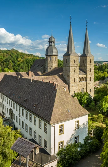 Luftaufnahme der Abtei Bursfelde mit zwei markanten Türmen, umgeben von üppiger grüner Natur.