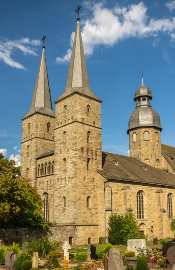 Stiftskirche St. Bonifatius in einer grünen Umgebung mit zwei Türmen, klarem Himmel im Sommer.
