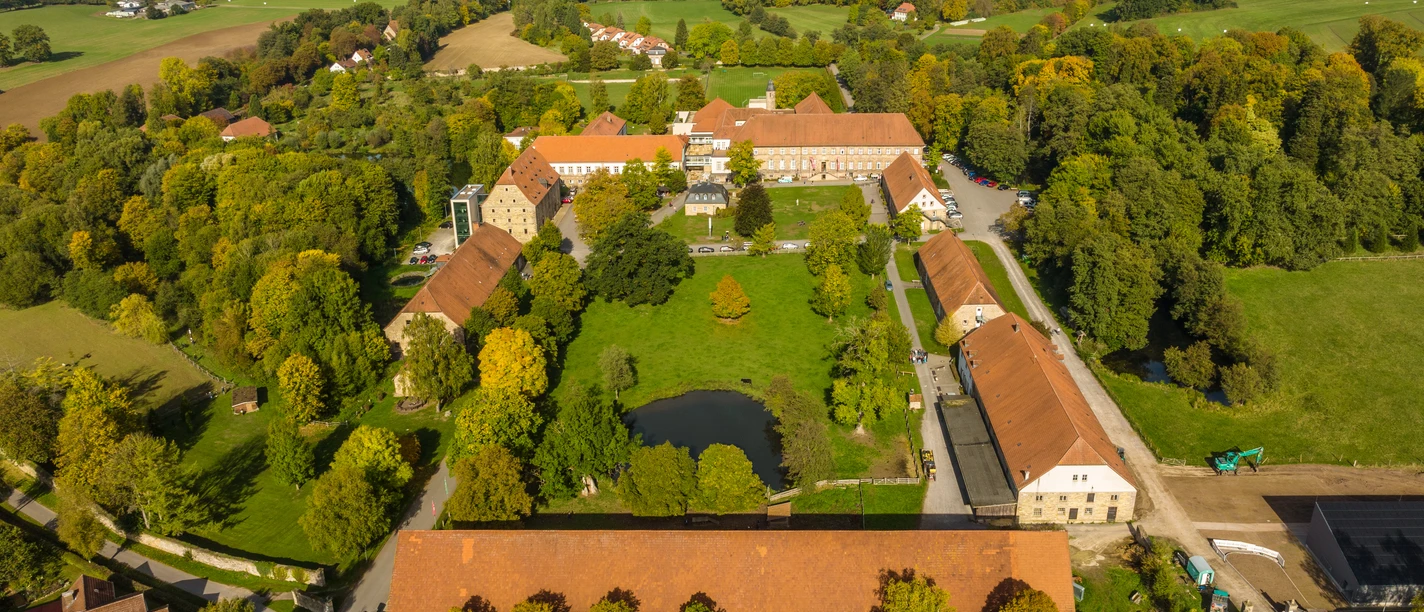 Warburg-Kloster Hardehausen-Teutoburger-Wald-Tourismus-D-Ketz-053-CC-BY-SA.jpg Luftaufnahme eines historischen Gutshofes, umgeben von grünen Feldern und dichten Wäldern.