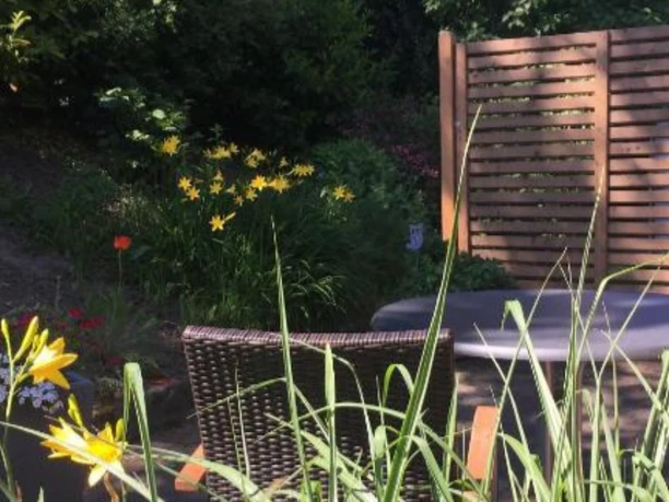 Terrasse Möblierte Terrasse mit Blick in einen dicht bepflanzten Garten mit gelben und roten Blumen.