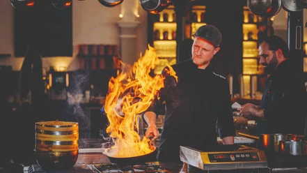 Restaurant Pferdestall im Gräflichen Park Mann brät im Restaurant Pferdestall das Essen, Feuer kommt aus der Pfanne raus.