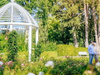 Rosengarten im Gräflichen Park, mit einem Monopteros und sich anguckenden Paar auf der anderen Seite. Rosengarten im Gräflichen Park, mit einem Monopteros und sich anguckenden Paar.