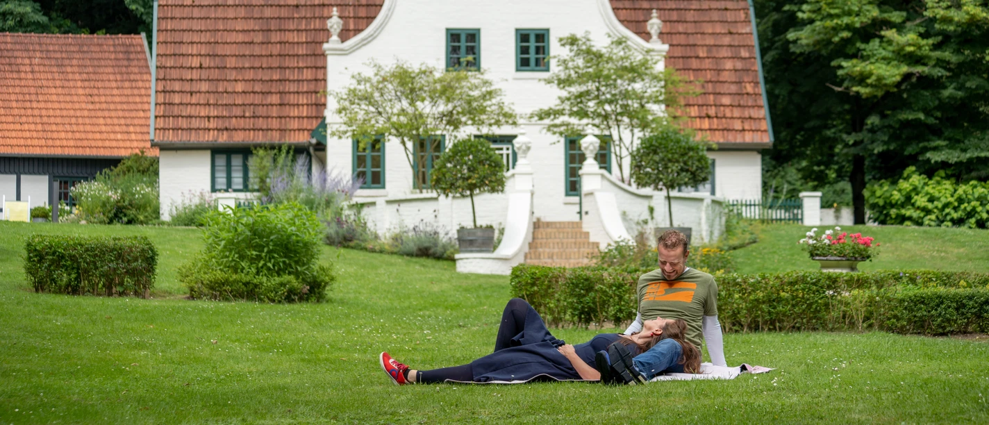 Im Künstlerdorf Worpswede Two people relaxing on a lawn in front of a white historic house in Worpswede.