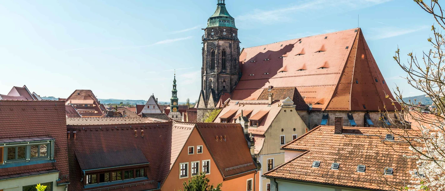 Blick zur Marienkirche Blick auf eine historische Stadt mit roten Ziegeldächern und einem großen Kirchturm unter klarem, blauem Himmel.