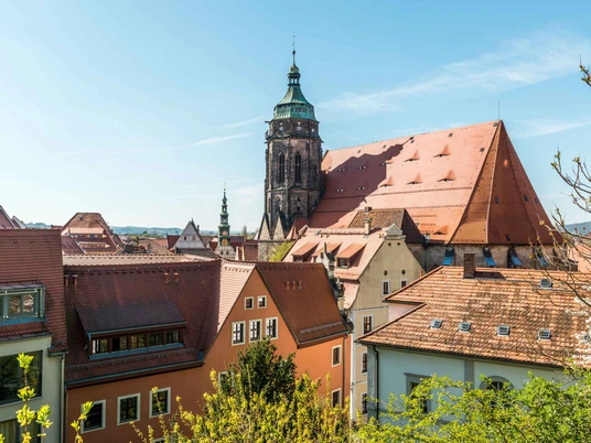 Blick zur Marienkirche Blick auf eine historische Stadt mit roten Ziegeldächern und einem großen Kirchturm unter klarem, blauem Himmel.