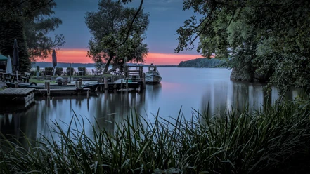 Sonnenuntergang Ratzeburger See.jpg Der Ratzeburger See bei Sonnenuntergang. Am Ufer ist ein Steg mit Booten.