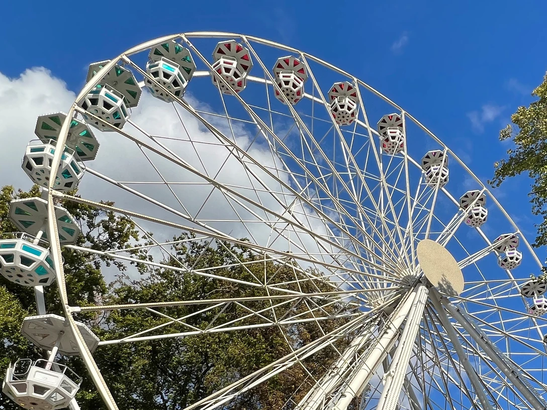 Domweih Verden Weißes Riesenrad in Verden vor blauem Himmel und Bäumen, fängt den fröhlichen Festcharakter ein.White Ferris wheel in Verden against a blue sky and trees, captures the cheerful festival character.Det hvide pariserhjul i Verden foran blå himmel og træer indfanger den muntre festivalkarakter.Het witte reuzenrad in Verden tegen een blauwe lucht en bomen geeft het vrolijke karakter van het festival goed weer.