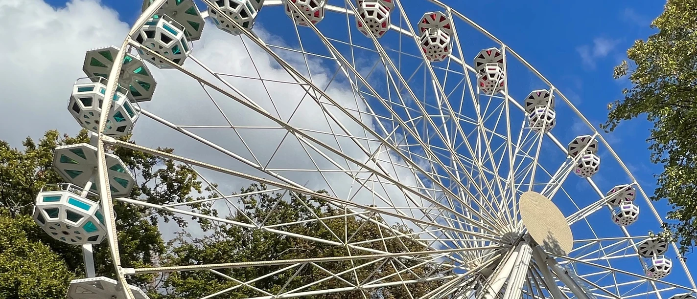 Domweih Verden Weißes Riesenrad in Verden vor blauem Himmel und Bäumen, fängt den fröhlichen Festcharakter ein.