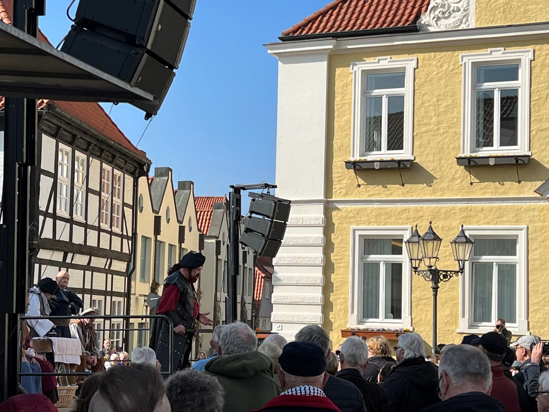 Läthare Spende Verden Ein mittelalterlich gekleideter Redner spricht zu einer Menge vor der historischen Kulisse Verdens.A speaker dressed in medieval garb addresses a crowd against the historic backdrop of Verden.En taler klædt i middelalderkostume taler til en folkemængde i Verdens historiske kulisse.Een spreker in middeleeuws kostuum spreekt een menigte toe tegen de historische achtergrond van Verden.