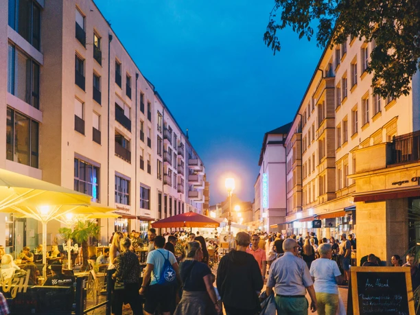 People stroll through the busy Gastromeile in Chemnitz at dusk.
