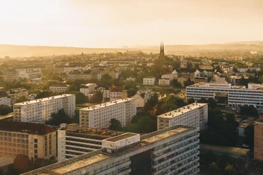 Luftbild Chemnitz_(c)Ernesto Uhlmann.jpg Stadtlandschaft von Chemnitz bei Sonnenuntergang, mit modernen Gebäuden und einer Kirche im Hintergrund.