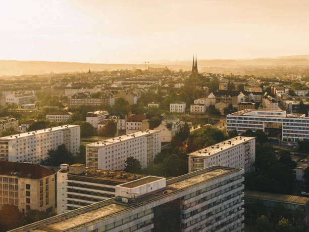 Luftbild Chemnitz_(c)Ernesto Uhlmann.jpg Stadtlandschaft von Chemnitz bei Sonnenuntergang, mit modernen Gebäuden und einer Kirche im Hintergrund.