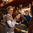 Früh im Veedel Szene in einem rustikalem Brauhaus, zwei Frauen stoßen mit Kölsch an.Scene in a rustic brewery: two women toast with Kölsch beer.