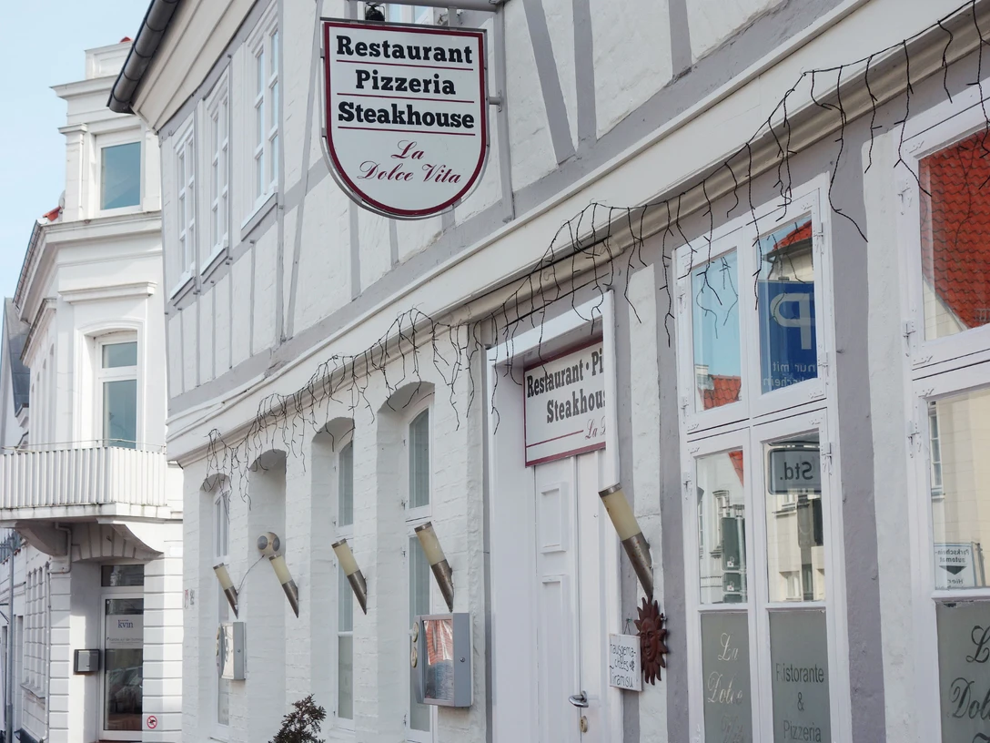 La-Dolce-Vita---Bernadette-Raffenberg-09.03.jpg Ansicht eines weißen Hauses mit einem Schild, auf dem „Restaurant-Pizzeria-Steakhouse“ steht