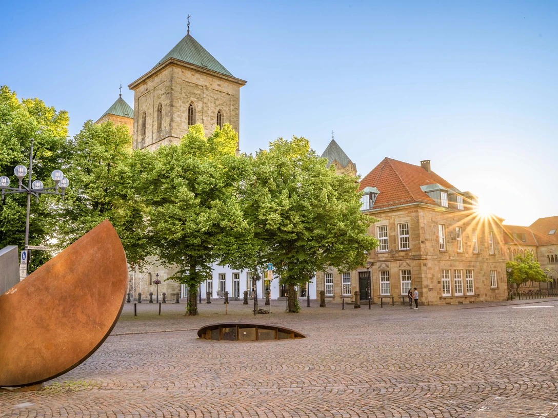 Cathedral and theatre forecourt Osnabrück Cathedral with adjoining theater forecourt, surrounded by trees, in bright sunshine.